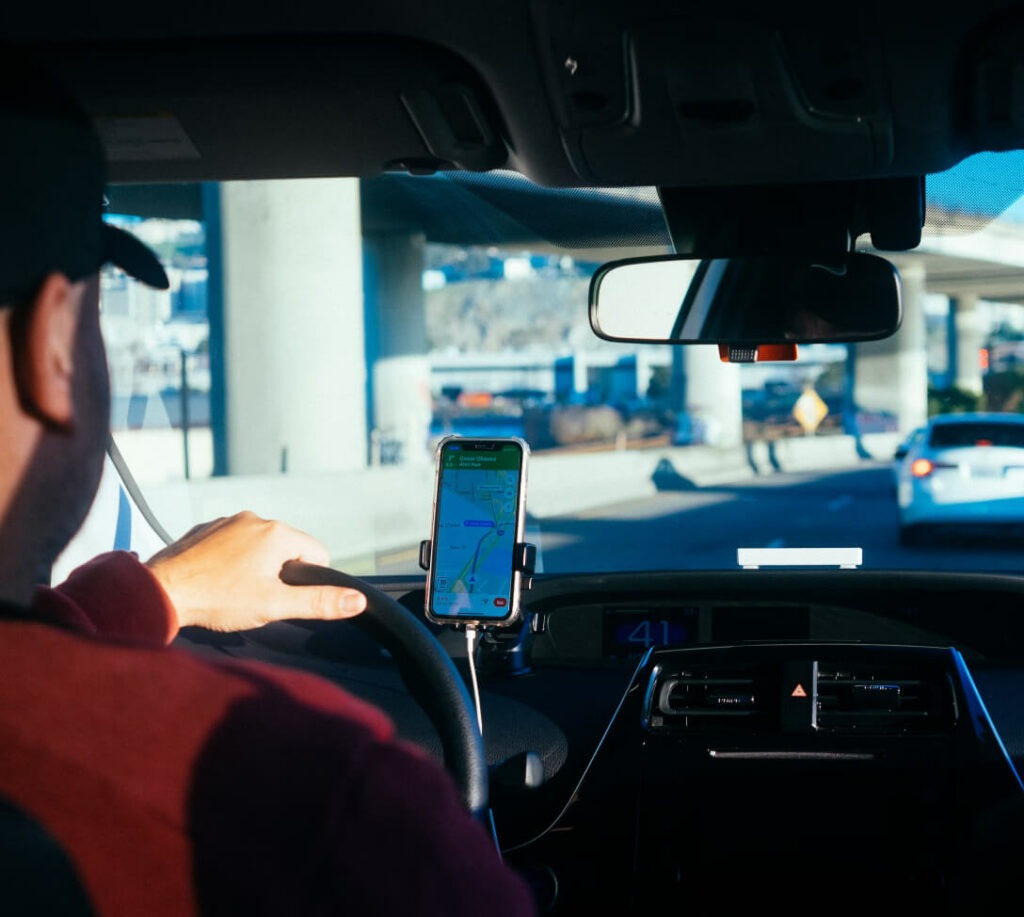 Man in rijdende auto die mobiele telefoon voor navigatie.