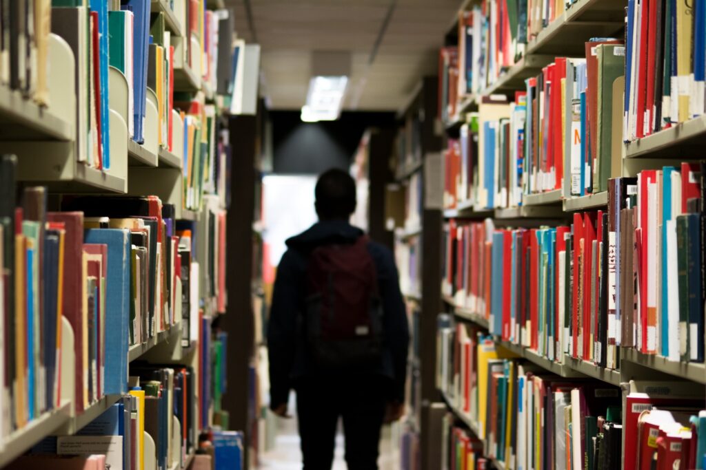 Een persoon die door een bibliotheek vol boeken loopt.